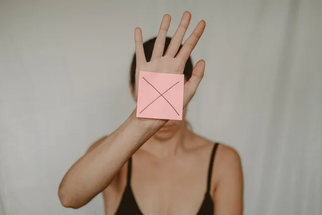 Unrecognizable young woman demonstrating prohibition sign showing gesture of refuse using hand and note with sign stop. Before you act on manipulation resistance exercises