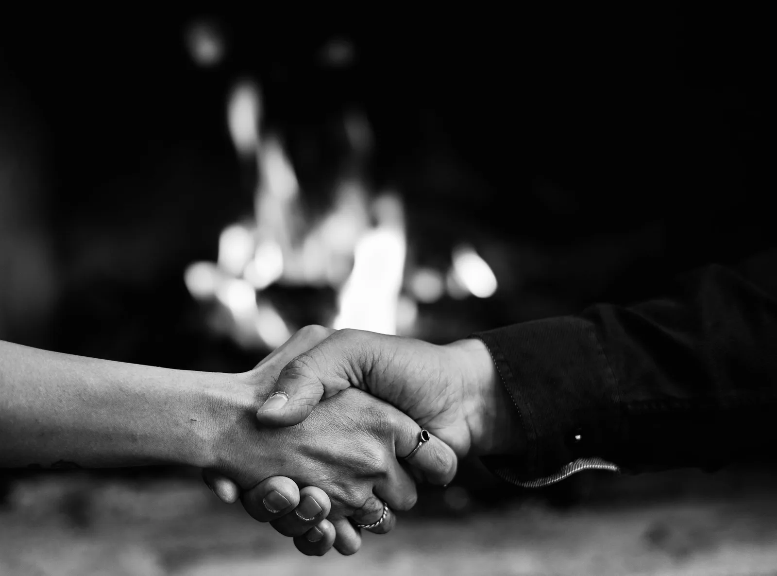 A captivating black and white image of a handshake in front of a warm fireplace. Reciprocity: telling a gift from a down payment