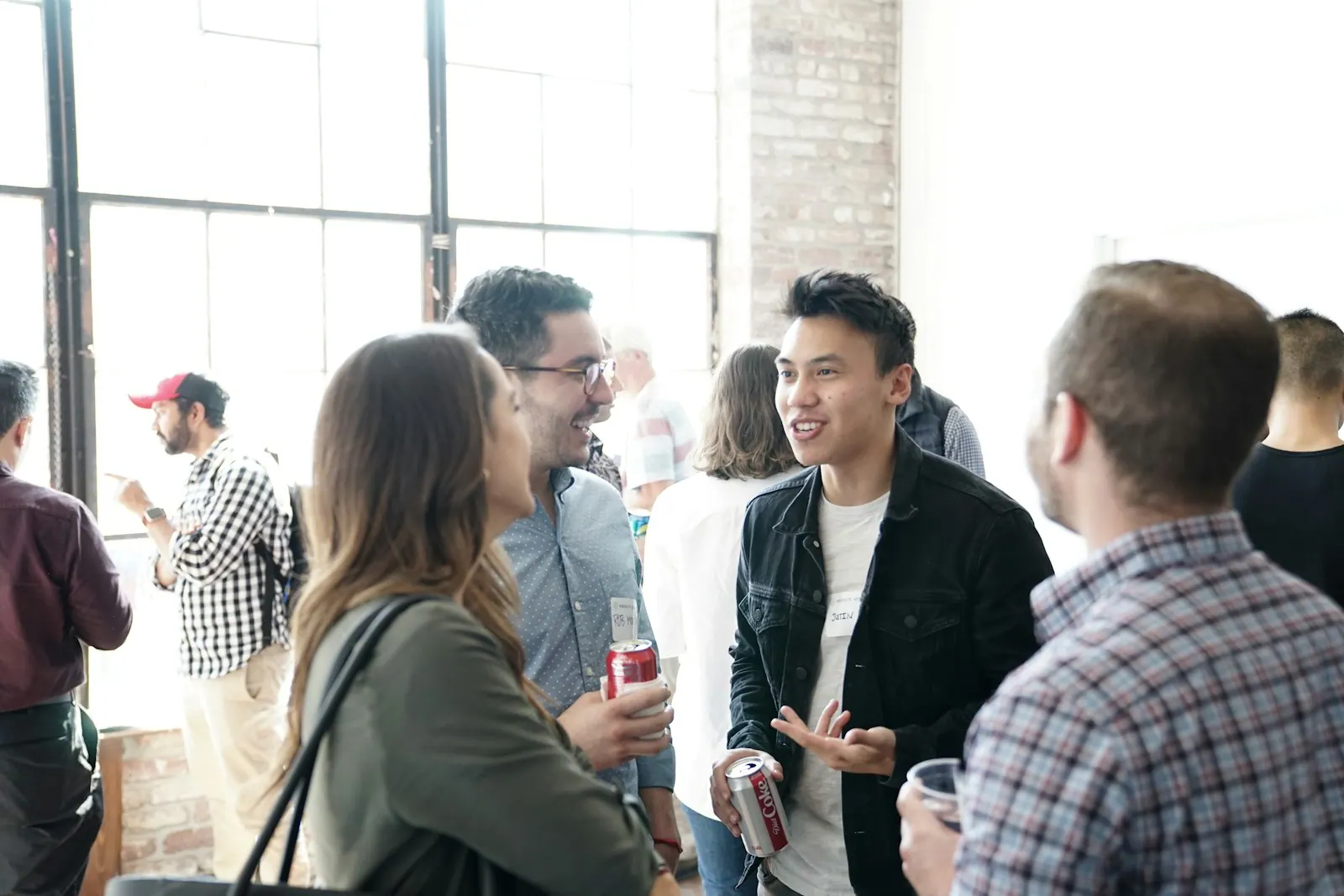 people gathering in room people having a conversation, talking, and smiling after an event in an open lobby. Social proof examples from work and everyday decisions